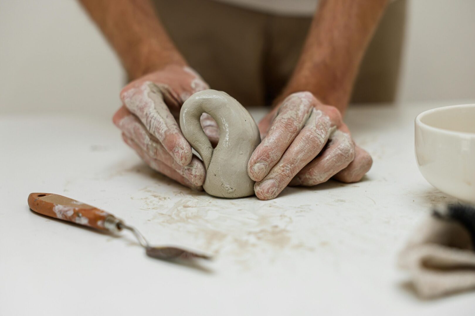 Hands molding clay into a shape.