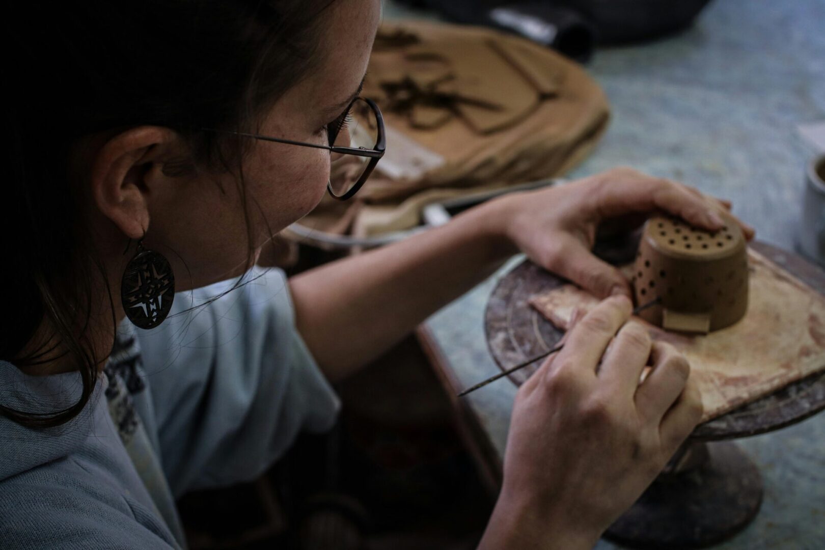 A woman working on pottery with a tool.