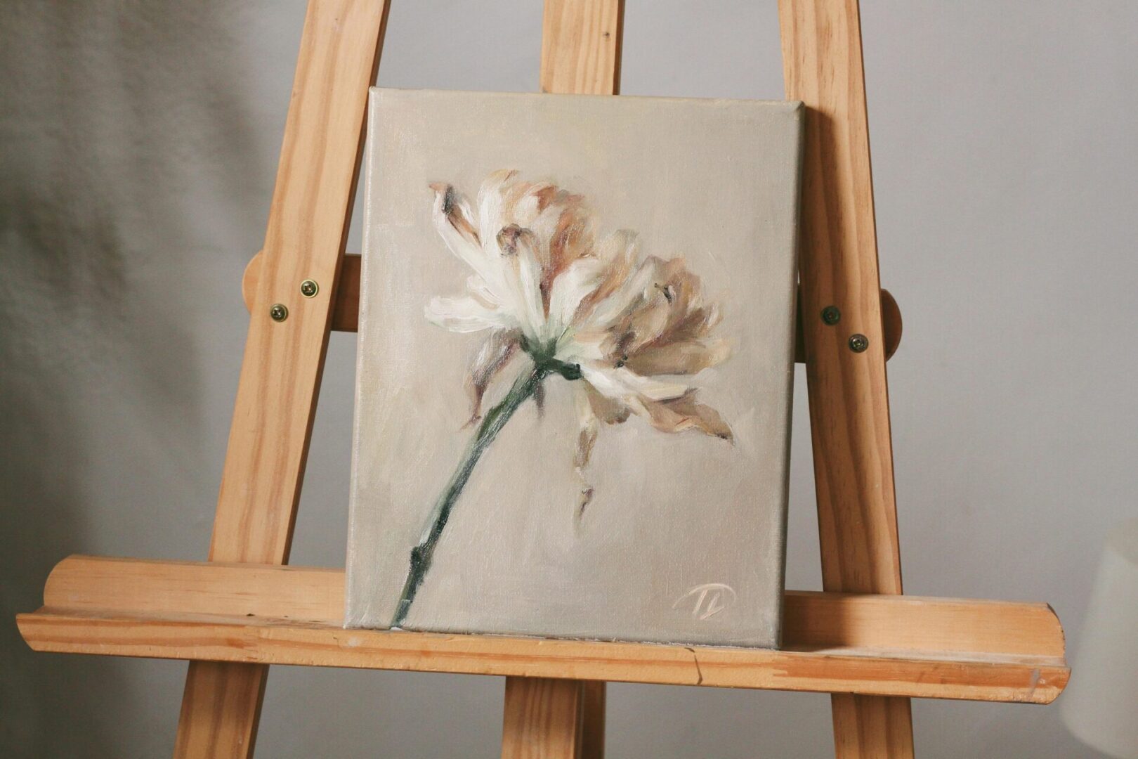 Oil painting of a white flower on an easel.