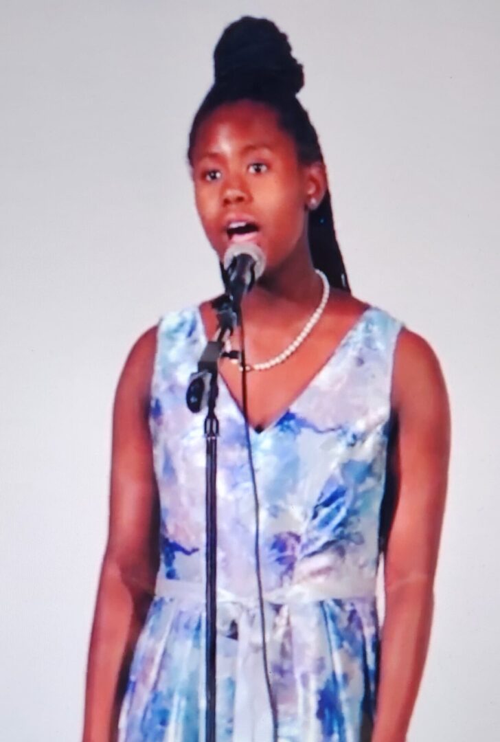 Young woman singing into a microphone.