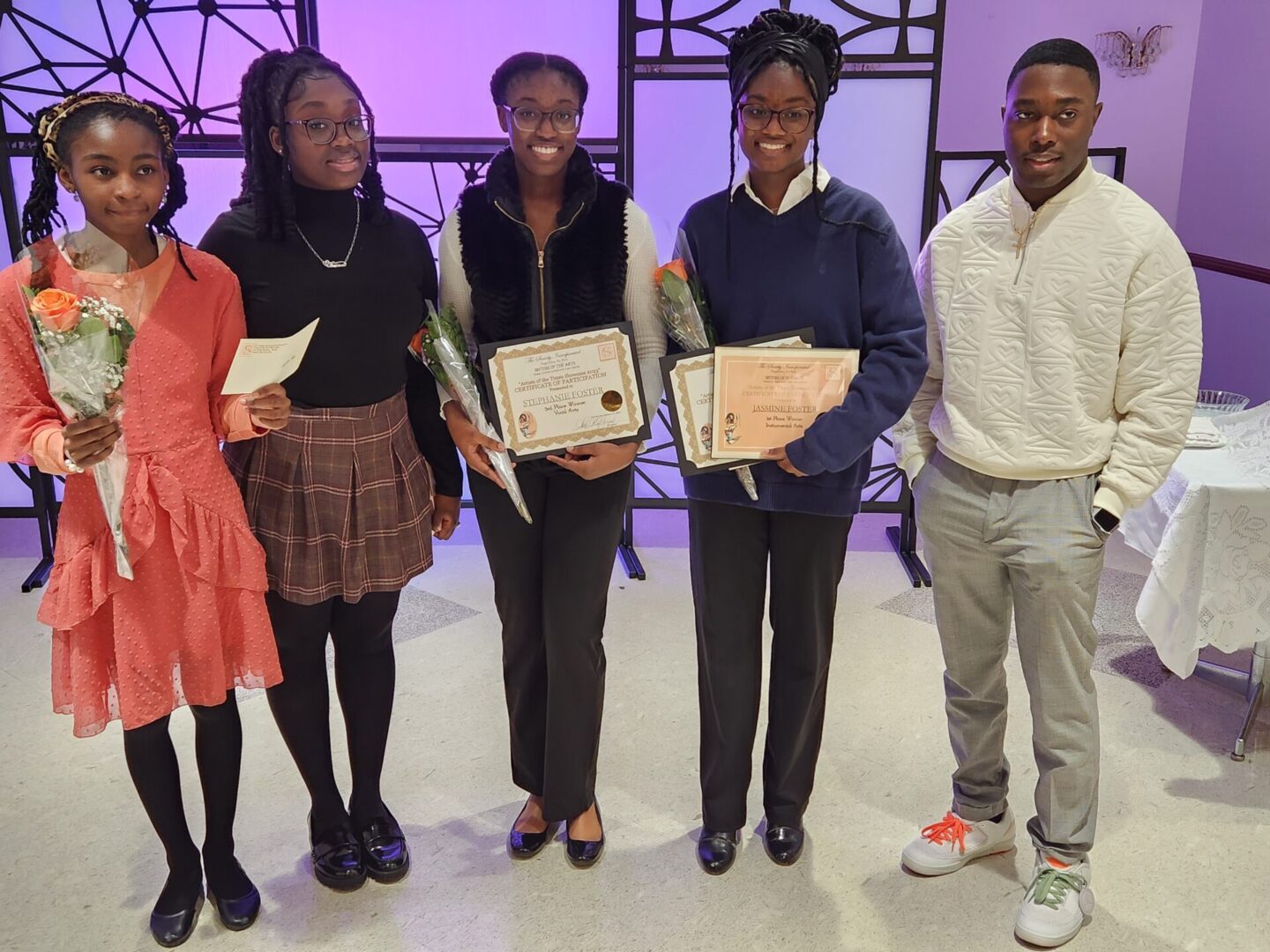 Four students holding certificates and flowers.